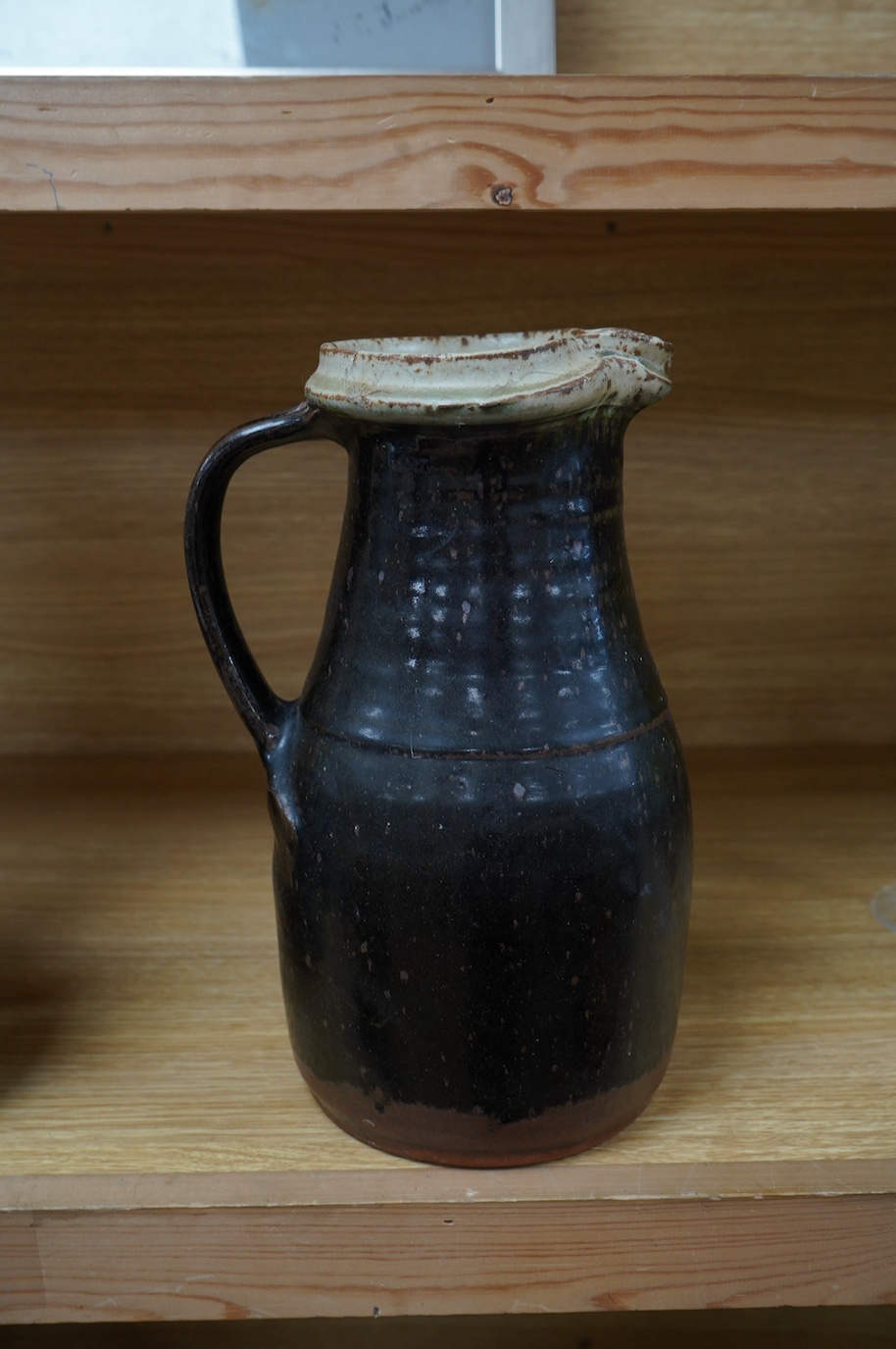 Richard Batterham (1936-2021), a tall stoneware black glazed jug, with a cream rim. 28cm high. Condition - good